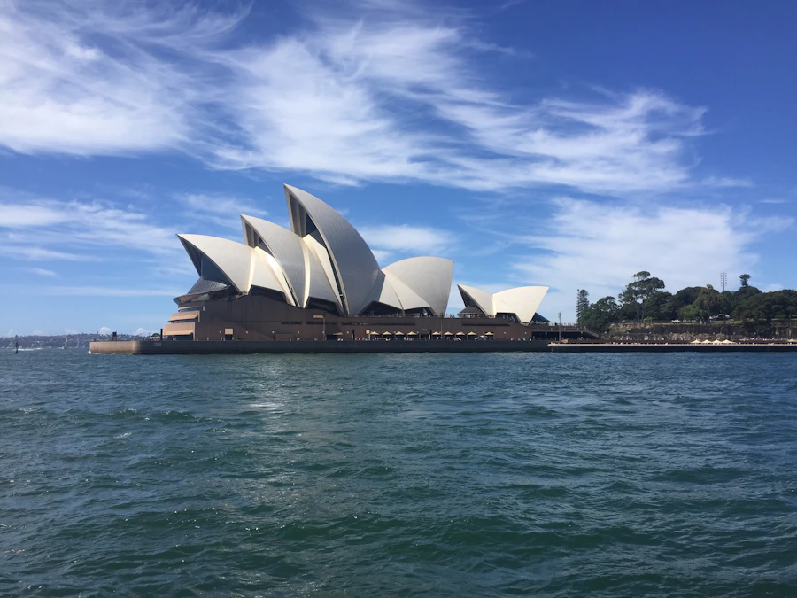 Sydney Opera House beside the harbour under a blue sky